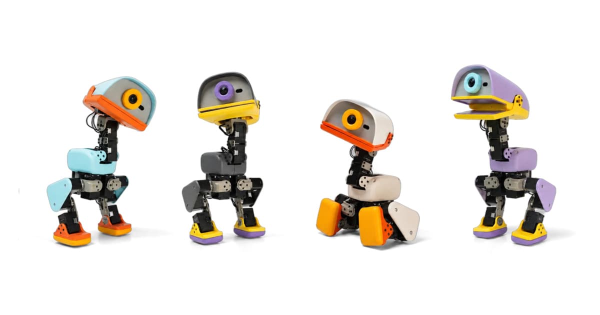 Microduck 双足机器人站立在桌面上,展示其紧凑的白色外壳和关节结构